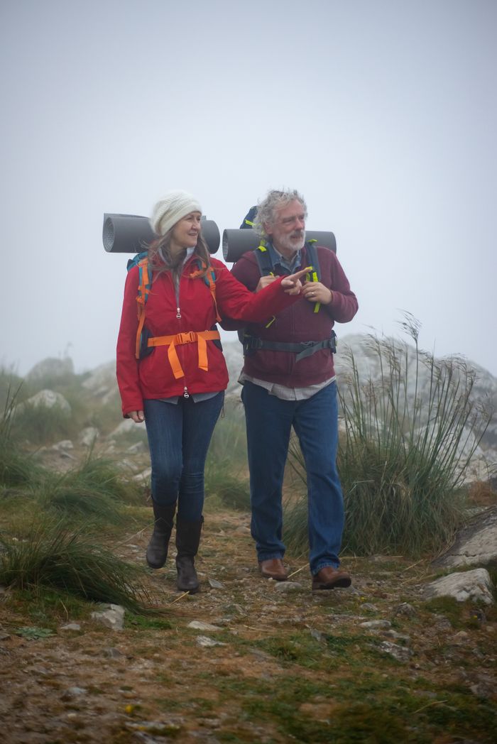 brand-01 Elderly couple hiking through foggy Portuguese trails, enjoying nature's tranquility.