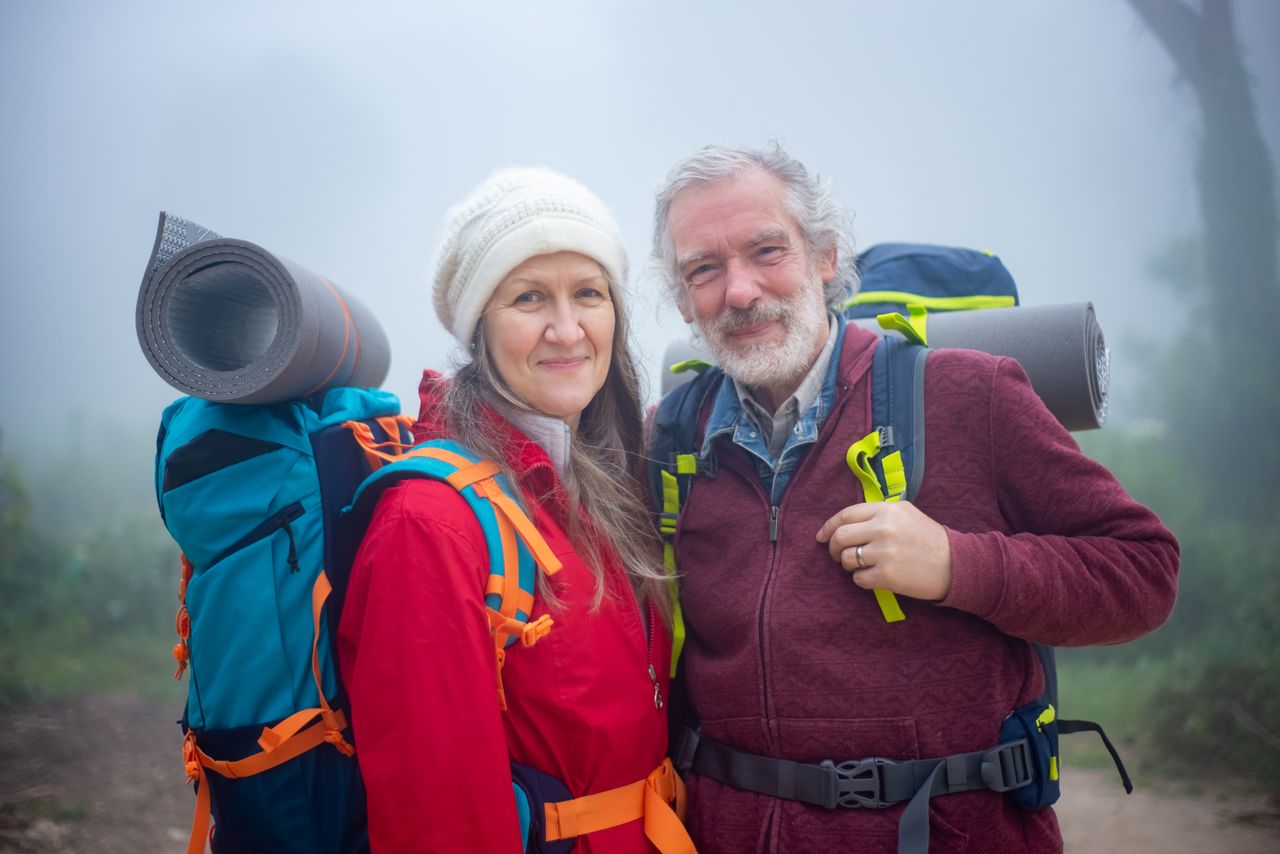 Senior couple hiking together in foggy scenery in Portugal, showcasing adventure and companionship.