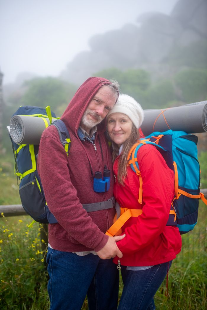 Senior couple hiking and embracing in misty Portugal, highlighting love and adventure in nature.